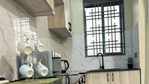 Uma cozinha com azulejos de mármore, uma janela com grade metálica e armários de madeira.