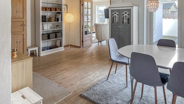 A dining area with a round table and chairs, a white cabinet with shelves, and a door leading to another room. - Beautiful home in Blokhus with WiFi (Blokhus)