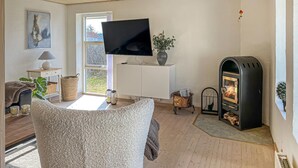 A living room with a TV, fireplace, and a view through a window. - Beautiful home in Blokhus with WiFi (Blokhus)