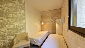 Ein kleines, gemütliches Zimmer mit einem Einzelbett, einem Sessel und einer Wand mit Muster.