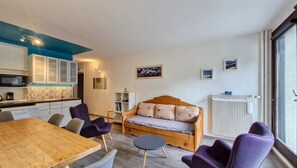 Ein gemütlicher Wohnbereich mit einem Holzsofa, einem Esstisch und violetten Stühlen.
