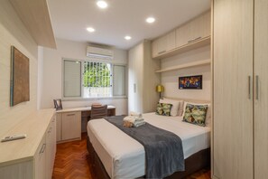 Een moderne slaapkamer met een bed, nachtkastje, bureau en kledingkast.