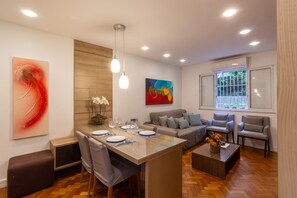 A modern living room with a dining area, wooden flooring, and contemporary artwork. - 10-min Walk to Copacabana Beach | STC302 (Rio de Janeiro)