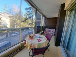 Ein Balkon mit Tisch und Stühlen, Blick auf die Straße und ein Fenster mit Jalousien.