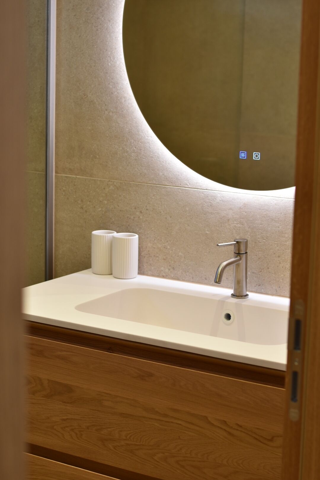 A bathroom with a white sink, a mirror, and a toilet paper holder.