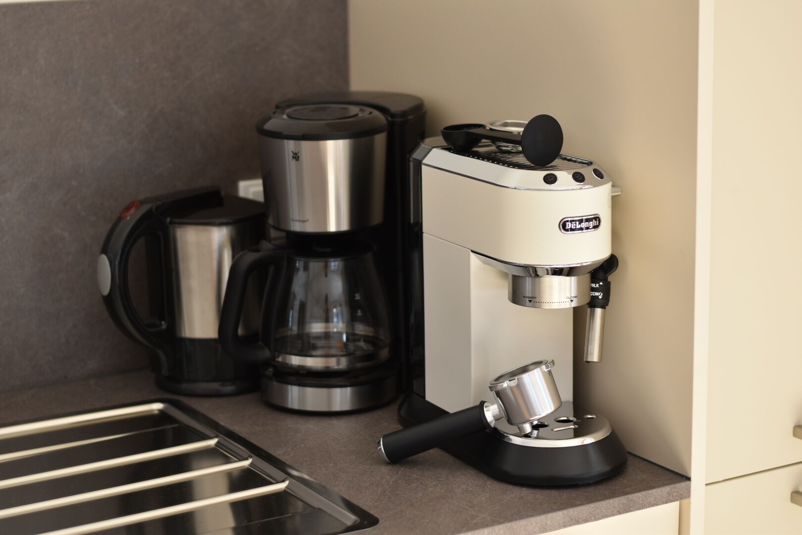 Eine Kaffeemaschine, eine Glaskanne und ein Topf auf einer Küchenarbeitsplatte.