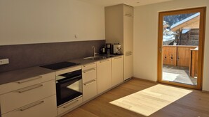 Una cocina moderna con horno integrado, cafetera y un amplio ventanal.