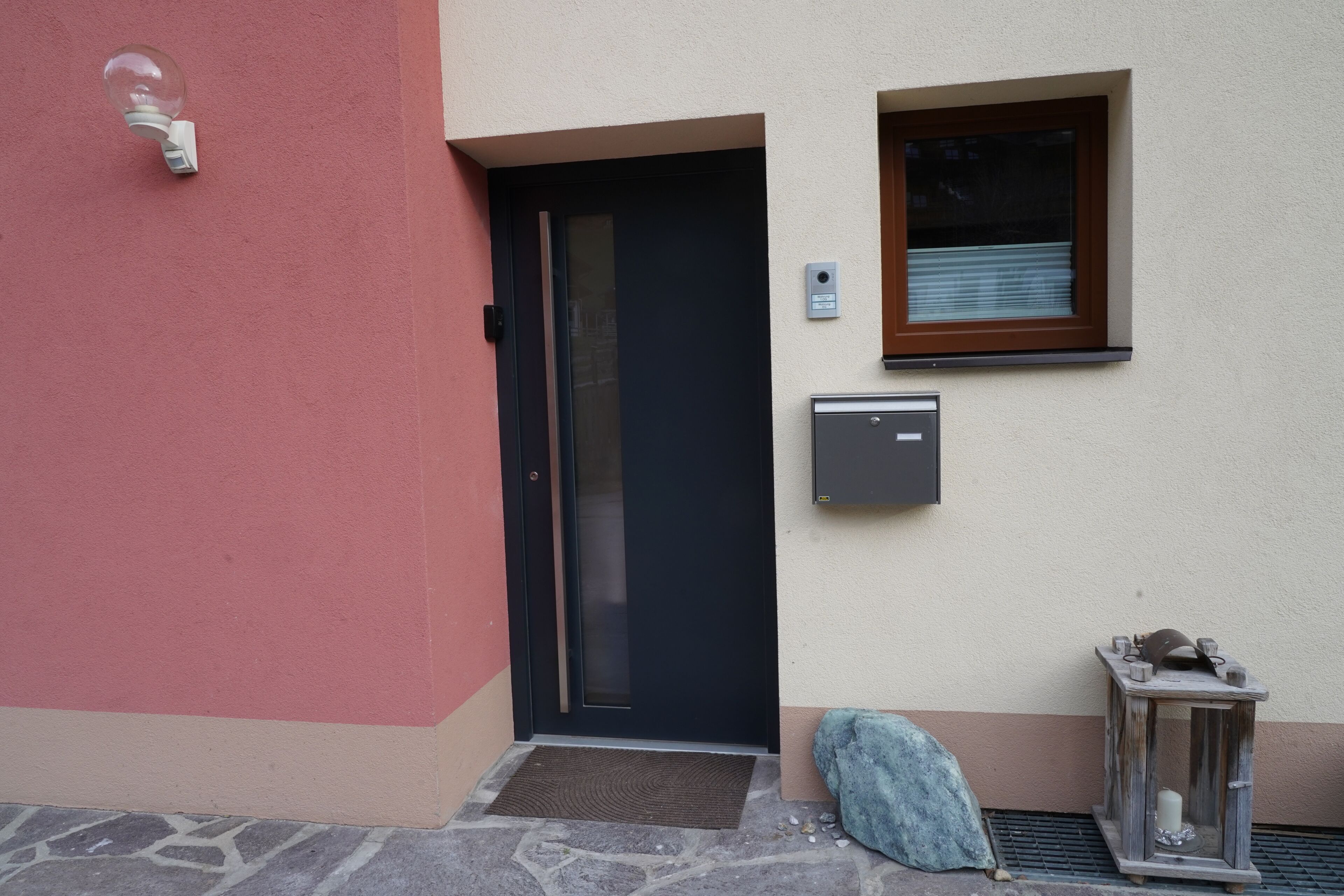 A door with a mail slot, a small window, and a mailbox on the wall.