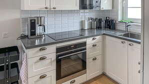 A modern kitchen with white cabinets, a built-in oven, a microwave, and a coffee maker.