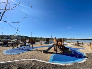 Un parque infantil con diversas estructuras de juego, un tobogán y una zona de arena.