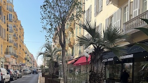 Una calle bordeada de edificios amarillos, palmeras y coches aparcados.