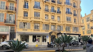 Un edificio de varios pisos con balcones, una entrada a nivel de calle y scooters estacionados.