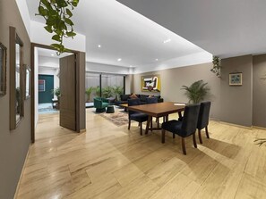 A spacious living area with a wooden dining table, dark upholstered chairs, and a green sofa set. A large window provides natural light, and the room features a modern ceiling design with recessed lighting. - 23-GH3 2 BR 2.5 Baths Private Patio Roma Norte (Ciudad de México)