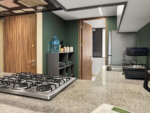 A modern kitchen with a gas stove, granite countertop, and wooden cabinets. - 23-GH3 2 BR 2.5 Baths Private Patio Roma Norte (Ciudad de México)