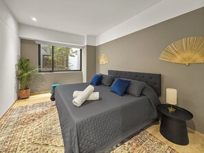A modern bedroom with a large bed, a bedside table, a potted plant, and a window. - 23-GH3 2 BR 2.5 Baths Private Patio Roma Norte (Ciudad de México)
