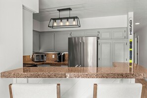 A modern kitchen with granite countertops, stainless steel appliances, and a pendant light fixture.