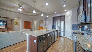A spacious kitchen with granite countertops, stainless steel appliances, and a large island. - Rhumba by Avantstay Game Room + Bakyard Oasis + Outdoor Dining Near Beaches and Downtown (Corpus Christi)