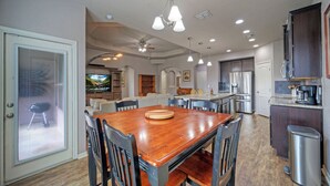 A spacious kitchen with modern appliances, a dining area with a wooden table and chairs, and a living area with a television and comfortable seating. - Rhumba by Avantstay Game Room + Bakyard Oasis + Outdoor Dining Near Beaches and Downtown (Corpus Christi)