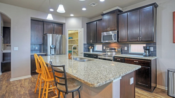 A modern kitchen with granite countertops, stainless steel appliances, and dark wood cabinets. - Rhumba by Avantstay Game Room + Bakyard Oasis + Outdoor Dining Near Beaches and Downtown (Corpus Christi)
