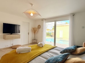Ein Schlafzimmer mit einem Bett, einem Fernseher, einem Fenster und Blick auf einen Pool.