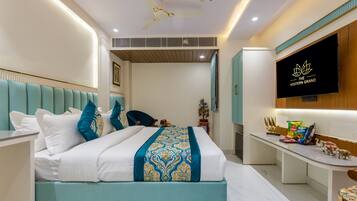 A modern hotel room with a bed, a desk, a TV, and a ceiling fan.
