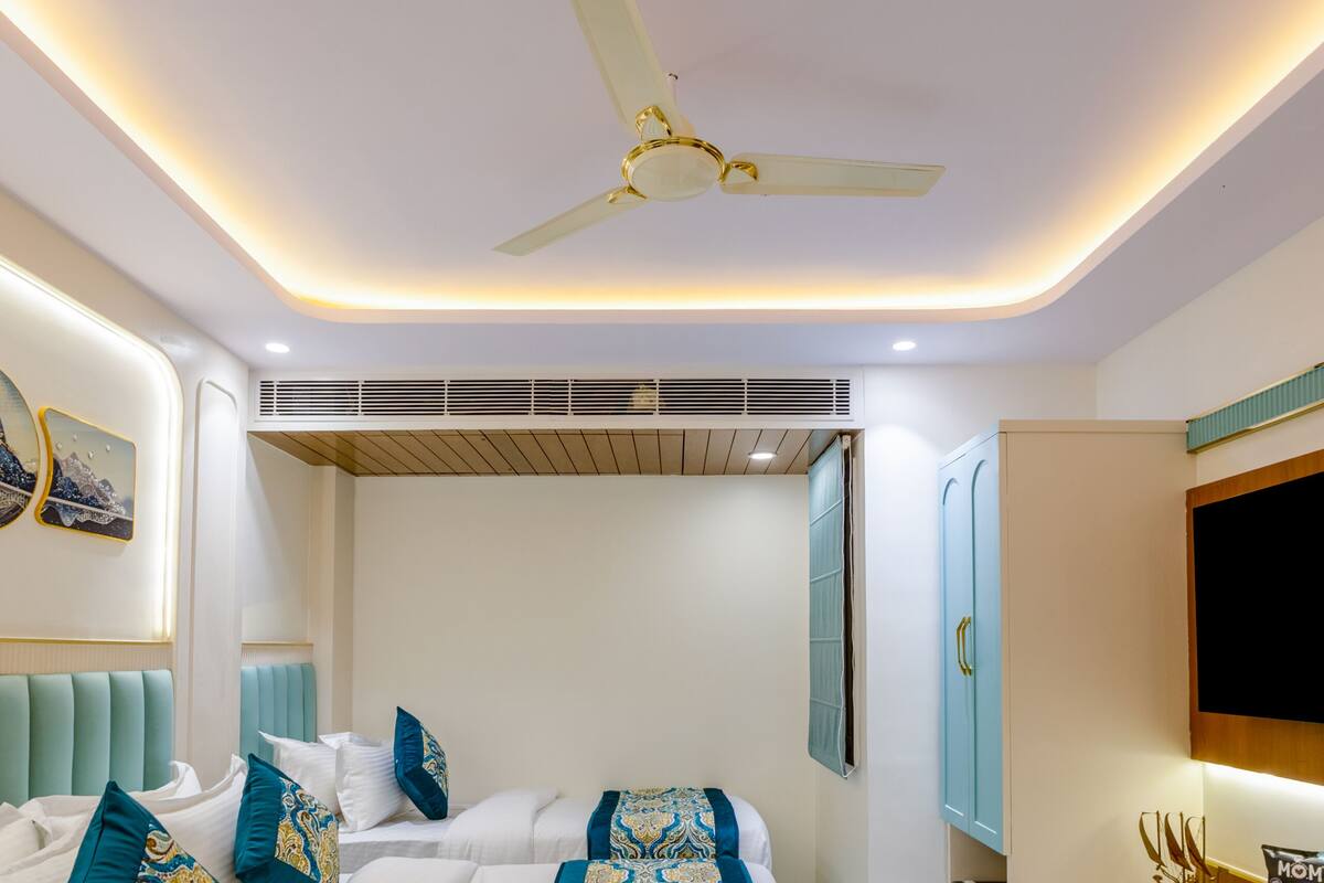 A modern bedroom with a bed, ceiling fan, and a TV.