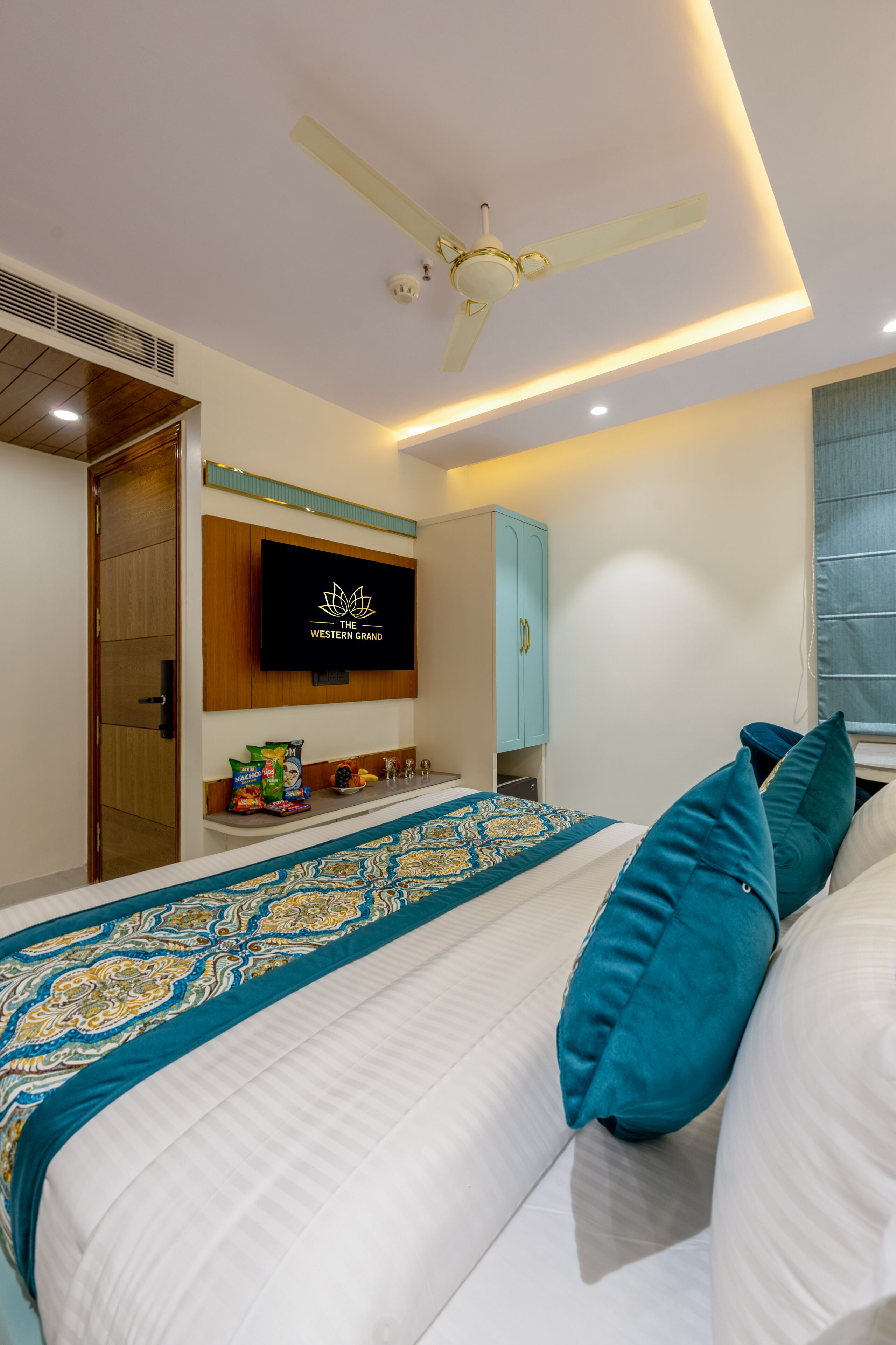 A modern bedroom with a bed, a ceiling fan, a TV mounted on the wall, and a wardrobe.