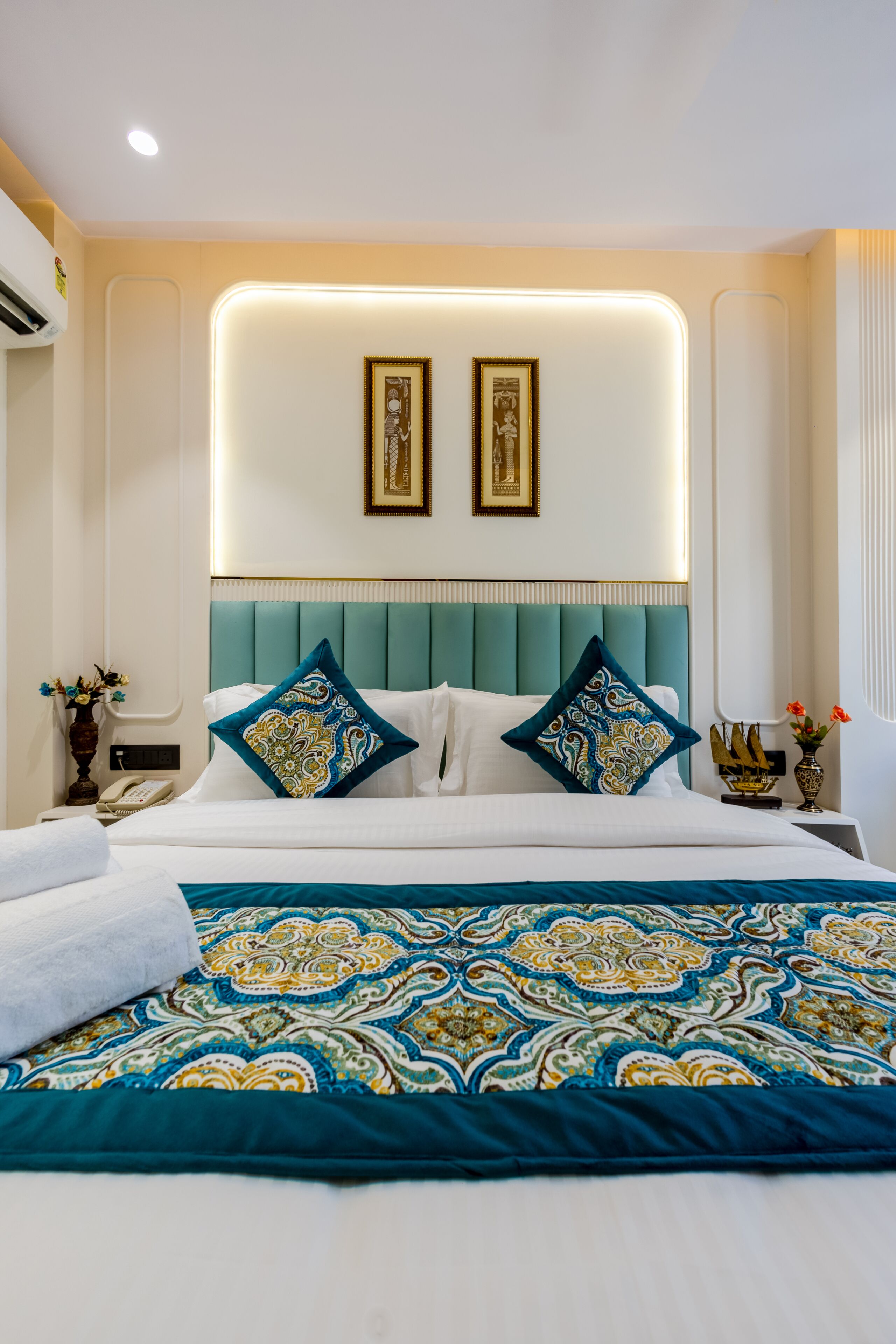 A hotel room with a bed, a nightstand, a lamp, and a wall-mounted picture.