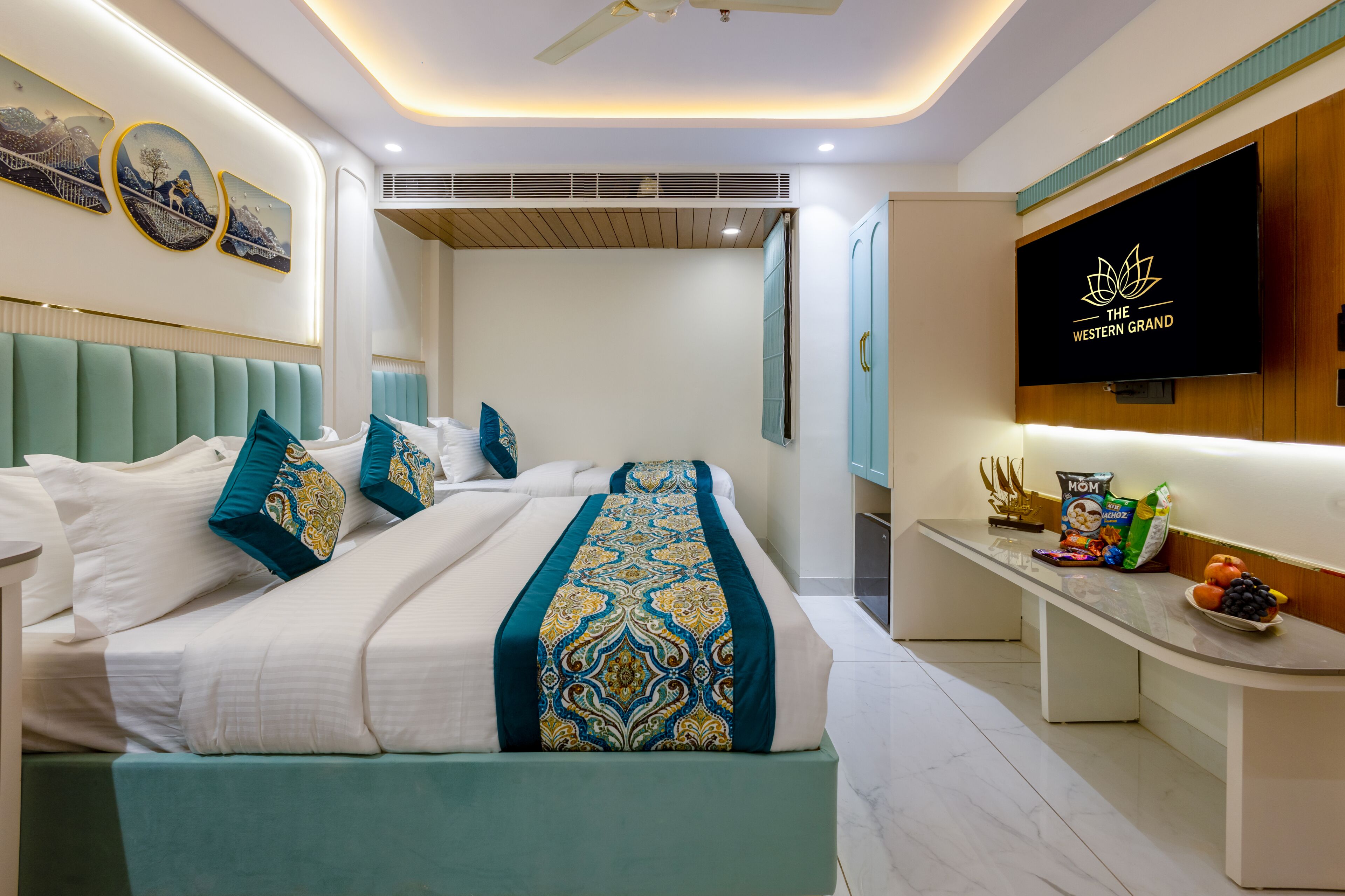 Une chambre d’hôtel moderne équipée d’un lit, d’une télévision, d’un bureau avec des collations et d’œuvres d’art accrochées au mur.