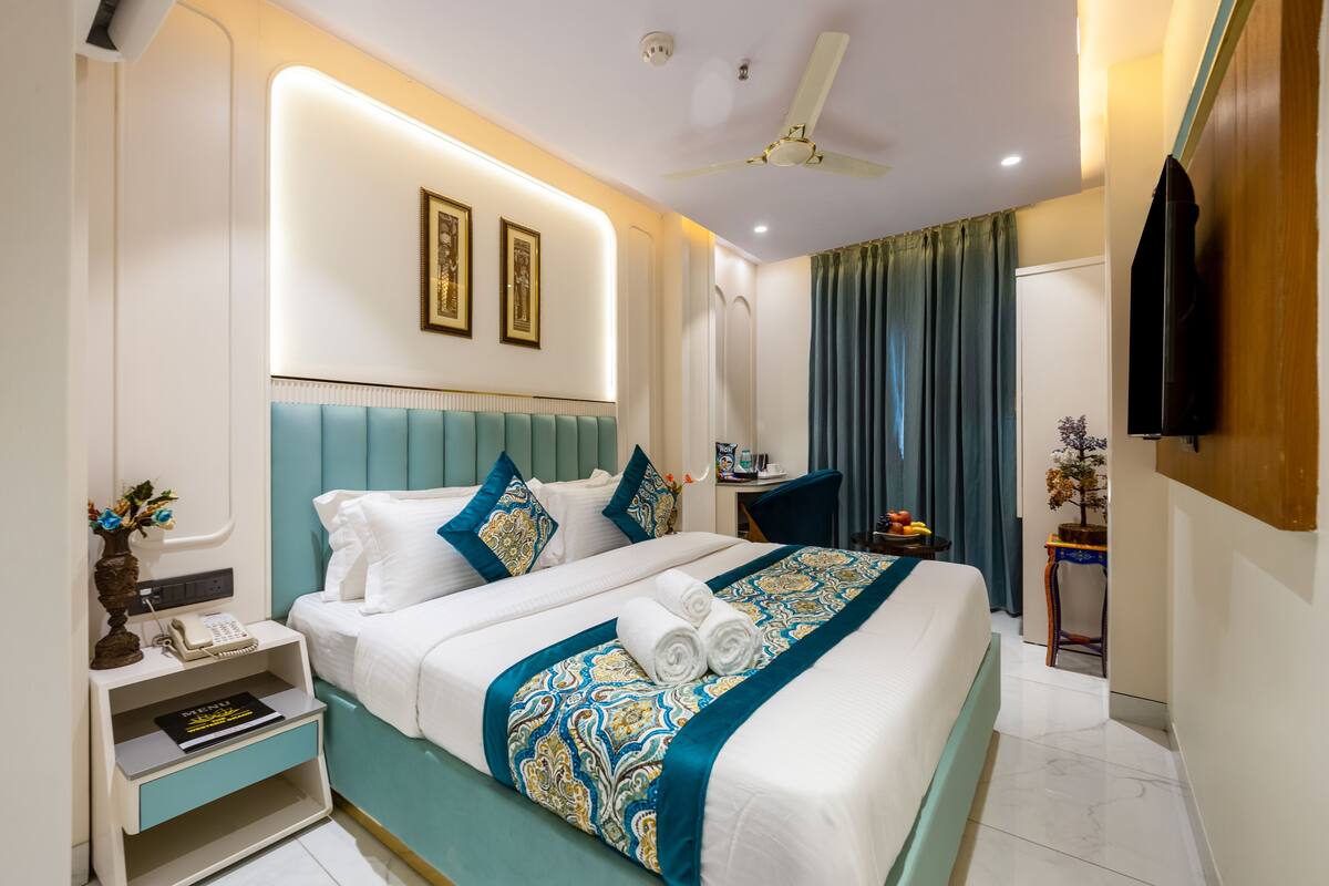 A modern hotel room with a bed, bedside table, and a television.