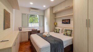 Quarto moderno com cama, mesa de cabeceira, escrivaninha e guarda-roupa.
