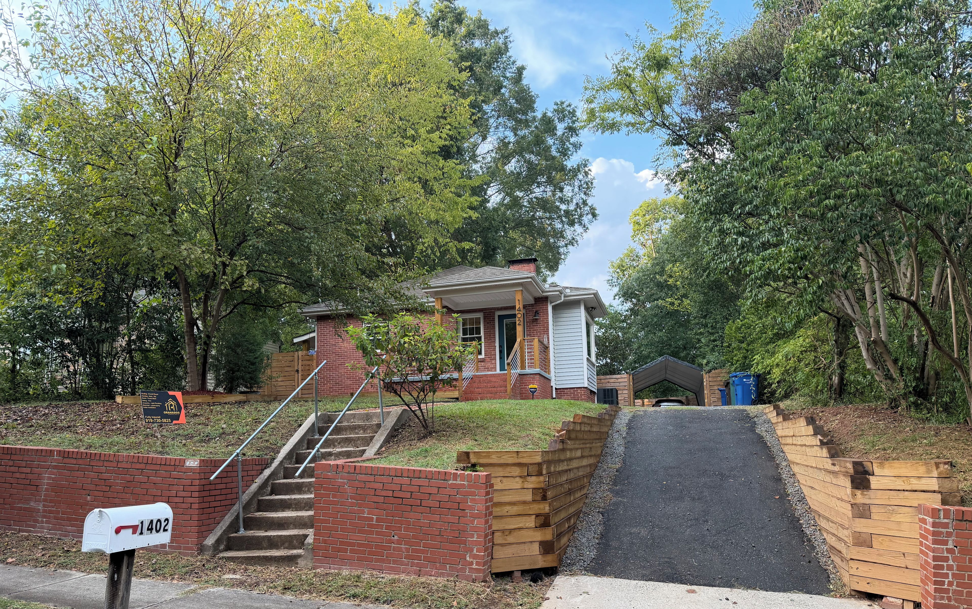 A residential property with a brick house, a mailbox, and a paved driveway.