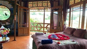 A room with a bed, a window, and a view of greenery.