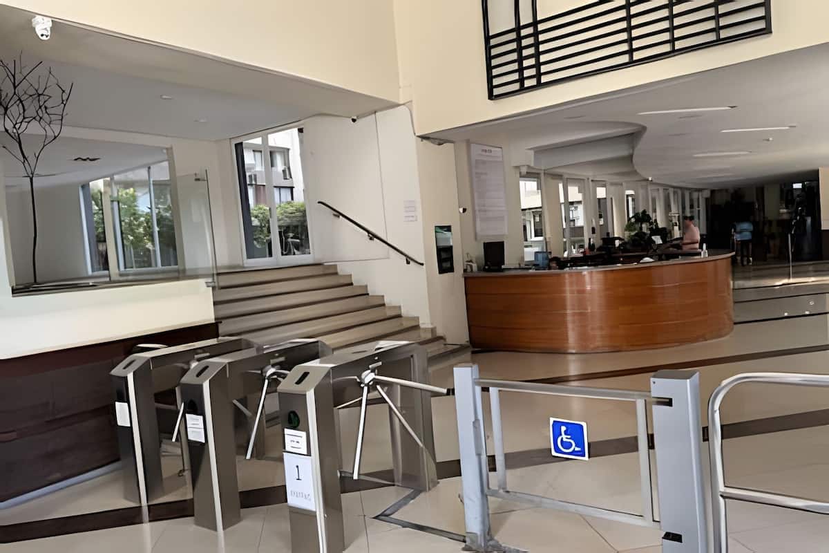 Un hall d'entrée moderne comprenant un comptoir d'accueil, un escalier et un panneau indiquant l'accessibilité aux personnes handicapées.