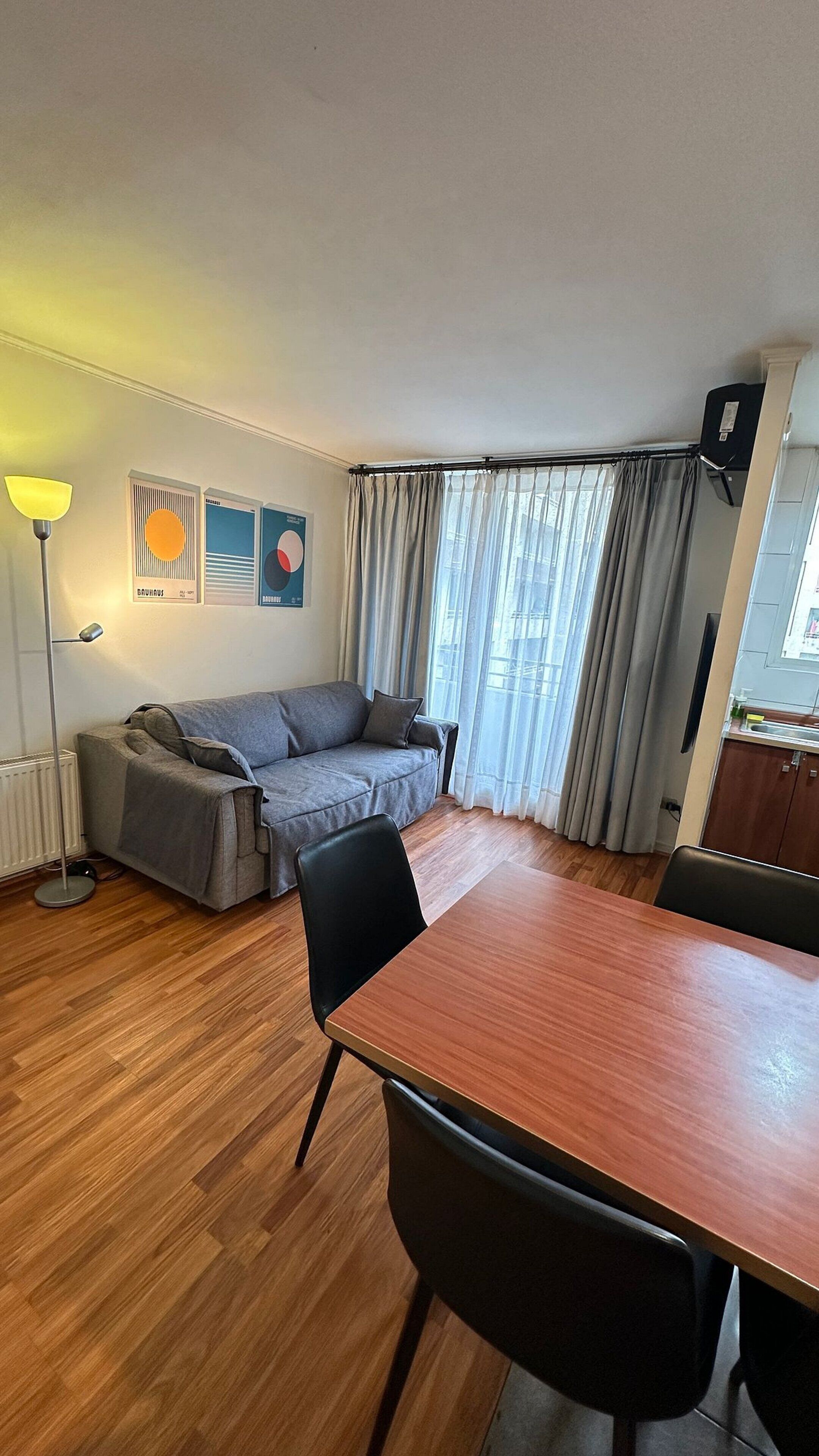 A living area with a sofa, a dining table, and a lamp.