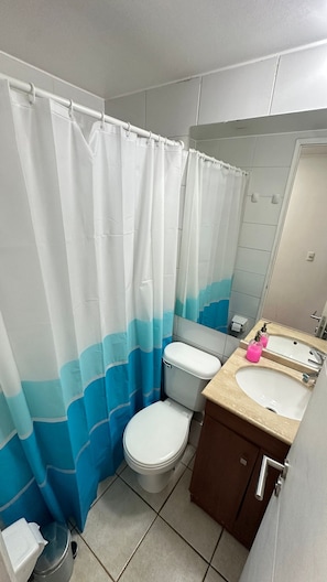 Un baño con inodoro, lavamanos y cortina de ducha.