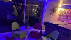 Une pièce dotée d’une cloison en verre, d’une table de billard et de chaises colorées.