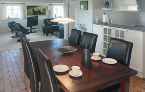 Ein Essbereich mit Holztisch, Stühlen, einem Fernseher und einer Küchenzeile mit Schränken und Spüle.