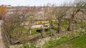 Ein Landhaus mit Strohdach, umgeben von Bäumen und einem eingezäunten Garten.