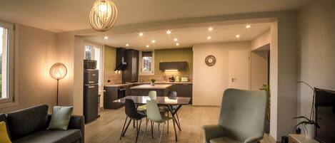 A modern living room with a sofa, a dining table, and a kitchen in the background.