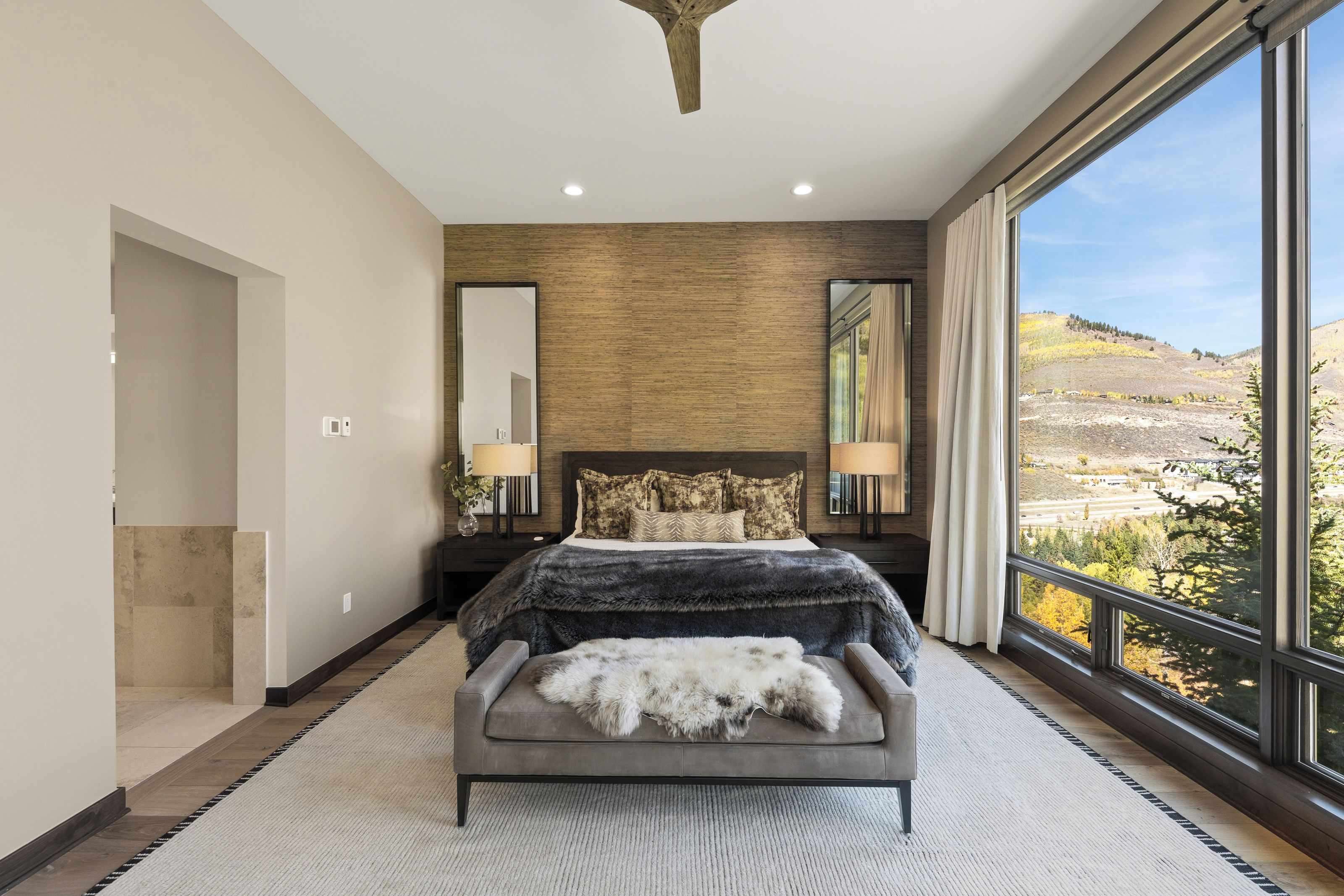 A bedroom with a large bed, a view of the outdoors, and a modern design.