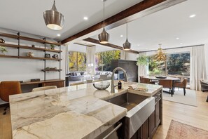 A modern kitchen with a marble island, pendant lighting, and a view of the outdoors. - Charming 5-Bedroom Home w/ Private Spa and A/C in Beautiful West Vail (Vail)