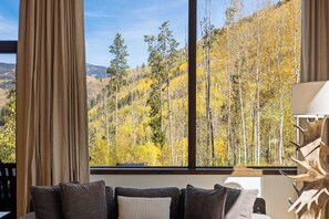 A room with a large window offering a view of a forested hillside. - Charming 5-Bedroom Home w/ Private Spa and A/C in Beautiful West Vail (Vail)