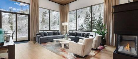 Una sala de estar moderna con chimenea, ventanas amplias y un espacio de estar acogedor.