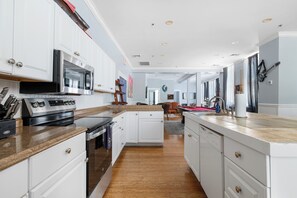 Eine moderne Küche mit weißen Schränken, einem eingebauten Backofen und einer Arbeitsplatte aus Granit.