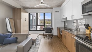 A modern kitchen with a large window, a dining area with a sofa and chair, and a ceiling fan. - Cozy Murphy Hideaway Studio 28 (Birmingham)