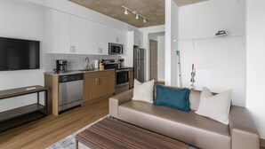 A modern kitchen with white cabinets, stainless steel appliances, and a flat-screen TV. - Cozy Murphy Hideaway Studio 28 (Birmingham)