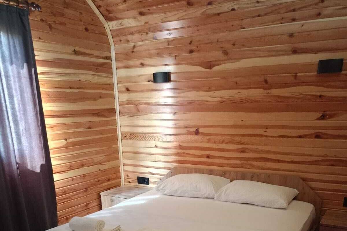 Habitación con paneles de madera, una cama, dos almohadas y toallas dobladas.