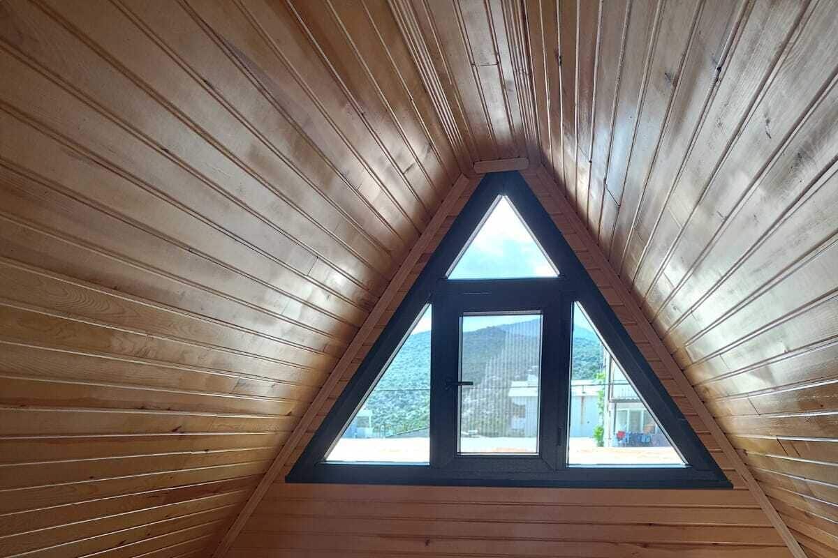 Un dormitorio acogedor en el ático con dos camas, paredes de madera, un tragaluz y vistas al exterior.