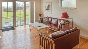A living room with a brown leather sofa, a white coffee table, and a red lamp.